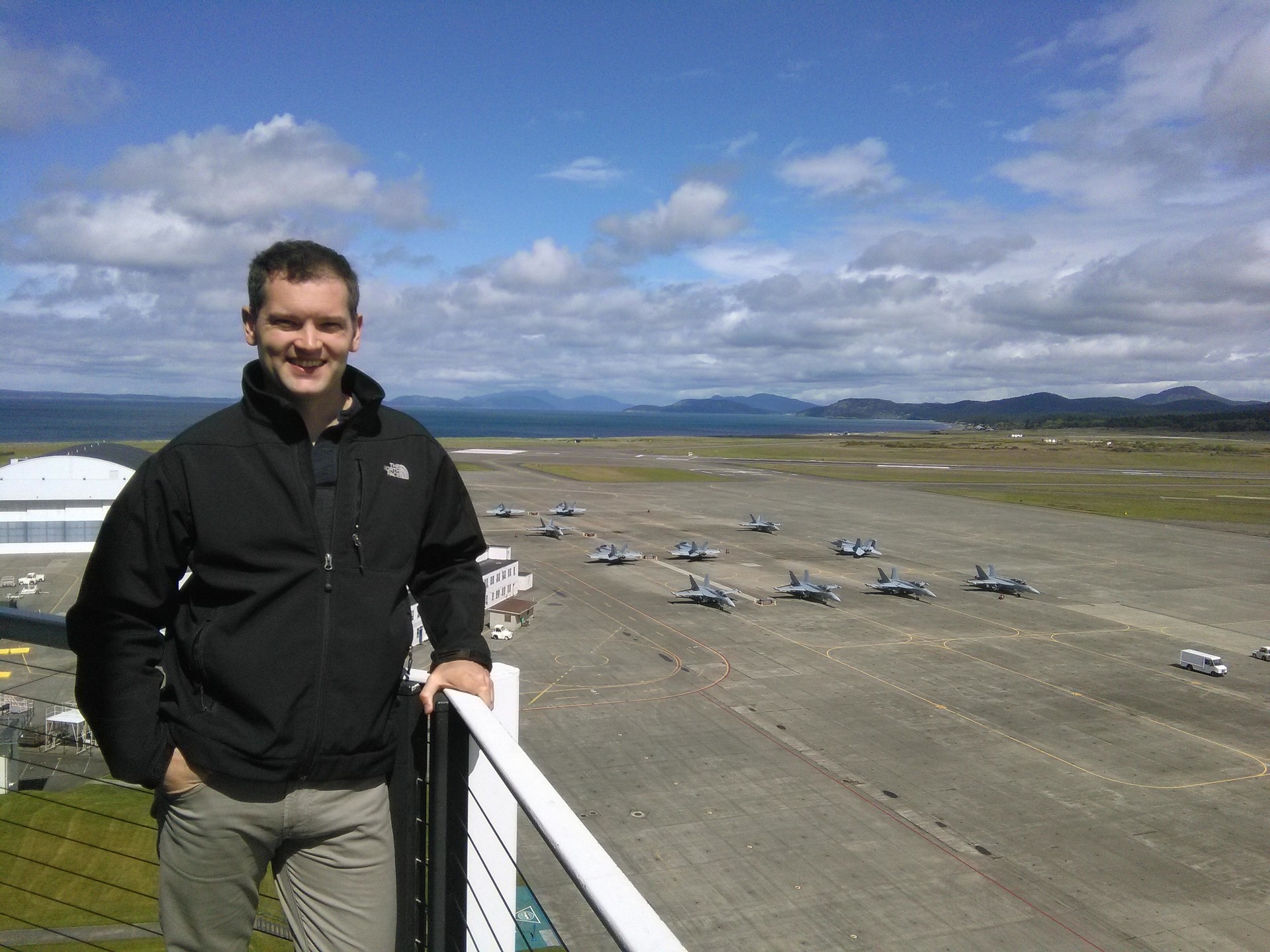 Ryan Keyes on an air station observation deck overlooking a flight line of fighter aircraft